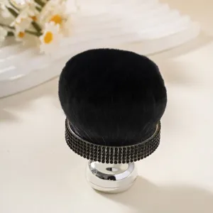 Detail of a large mushroom-head powder brush with luxurious black rhinestone handle.
