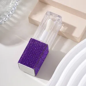 Close-up of a purple rhinestone-encrusted lid on a clear refillable lip gloss bottle.