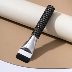 Macro view of a luxury flat foundation brush featuring a sparkling black rhinestone handle.
