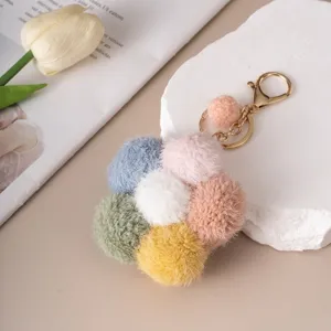 Detail of a colorful plush flower keychain with fuzzy balls and gold hardware