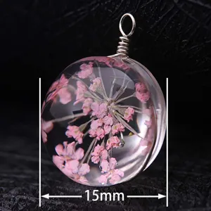 Macro view of a 15mm round glass pendant containing delicate pink dried flowers
