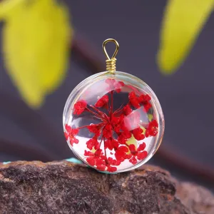 Detailed macro view of a clear glass ball pendant with red dried flowers on a stone.