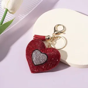 Close-up of sparkling rhinestone heart keychain with a vibrant red tassel detail.