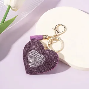 Close-up of a sparkling purple heart keychain with rhinestones and a silk tassel.