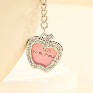 Detailed macro view of silver apple-shaped keychain with rhinestones and mini photo frame