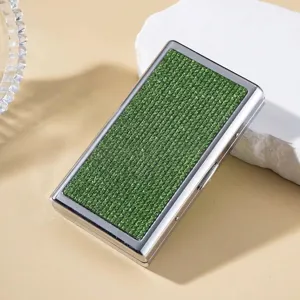 Close-up detail of silver cigarette case with sparkling green rhinestone inlay