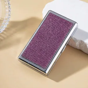 Detail view of a portable silver metal cigarette case with purple rhinestone inlay design