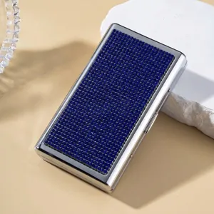 Detailed macro view of a silver metal cigarette case fully inlaid with sparkling blue rhinestones