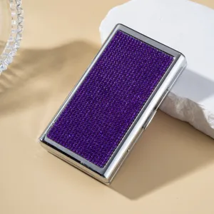 Luxury purple rhinestone-encrusted cigarette case with silver-tone frame on stone prop