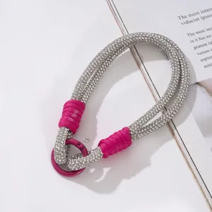 Detailansicht einer silbernen Strass-Handy-Handschlaufe mit magentafarbenen Akzenten.