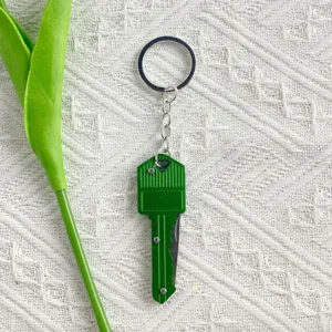 Detail view of a green key-shaped folding mini knife keychain for outdoor unboxing