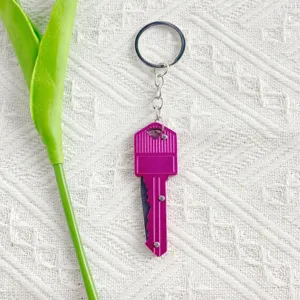Detail view of a purple key-shaped folding knife on a white textured background