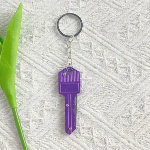 Close-up of portable purple key-shaped folding pocket knife keychain tool for outdoors