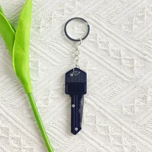 Close-up of a black key-shaped folding pocket knife on a textured background
