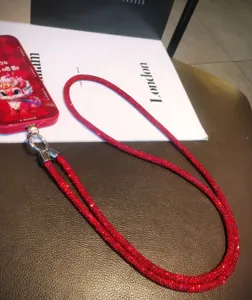 Primo piano di un cordino per cellulare di lusso con strass rossi e gancio argento