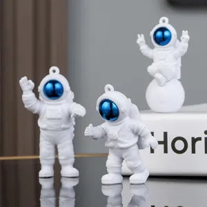 Detailed close-up view of cute PVC astronaut keychains with blue visors and hanging rings.