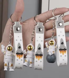 Detailed close-up shot of cute astronaut keychains featuring silicone straps and gold helmets.
