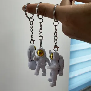 Close-up detail of cute astronaut keychains with PVC soft rubber figures and shiny gold visors.