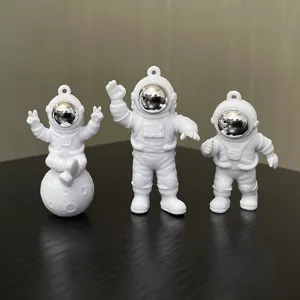 Detail shot of cute white astronaut keychain pendants with reflective silver visors.