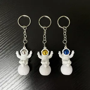 Astronaut keychain detail shot showing three spaceman pendants with silver, gold and blue visors.