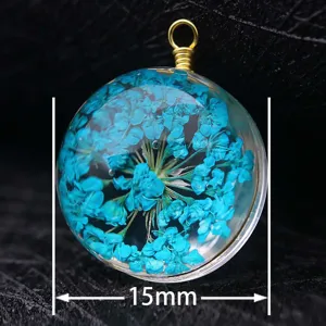 Detail showing a 15mm round glass pendant with blue dried flowers and a gold wire loop.