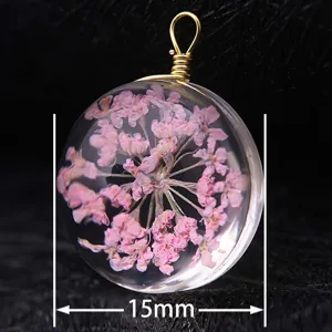 Macro detail of a 15mm round glass pendant featuring preserved pink dried flowers