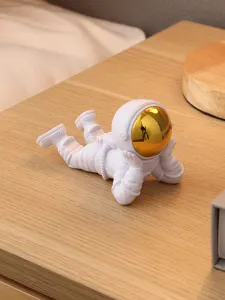 Gros plan sur les détails d'un mignon support de téléphone astronaute blanc sur une table en bois.