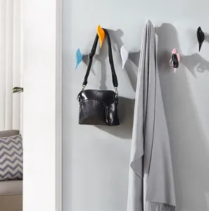 Decorative bird-shaped wall hooks used for hanging a black leather bag and grey scarf