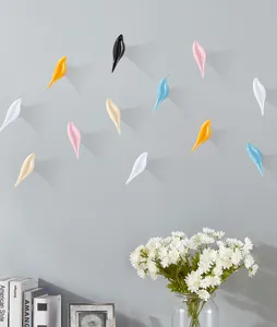 Detail view of modern multi-colored bird-shaped decorative wall hooks on a minimalist grey wall