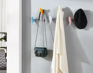 Close-up of colorful bird-shaped wall hooks holding a bag, scarf, and hat in an entryway