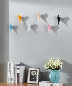 Modern bird-shaped decorative wall hooks in multiple colors installed on a gray wall.