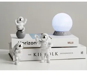 Close-updetails van creatieve astronautenfiguurtjes en gloeiende maanlamp bureaudecoratie.