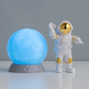 Creatief astronautenbeeldje en gloeiende maanlamp set voor kinderkamer en bureaudecoratie.