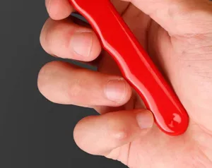 Handheld red tool sharpener detail close up showing ergonomic handle design and finish.