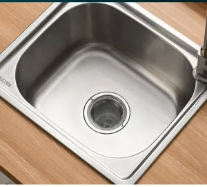Détail d'évier de cuisine en acier inoxydable montrant la surface lisse du bac et le filtre.