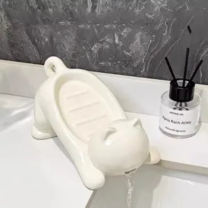 White ceramic cat shaped soap dish with drainage spout for bathroom washbasin sink detail.