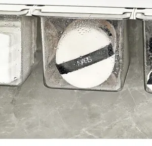 Transparent drawer organizer detail showing a white makeup puff with black ribbon inside.