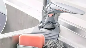 Detailed view of kitchen faucet sink caddy hanging storage with sponge and pink soap.