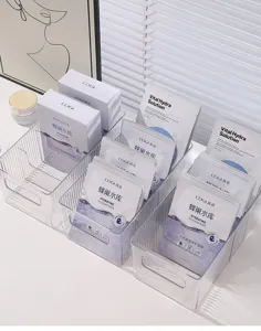Three transparent acrylic mask storage boxes organizing skincare sheets on a vanity