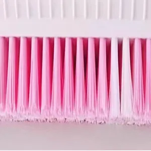 Close-up detail of cleaning laundry brush bristles, dense pink and white synthetic fiber design.