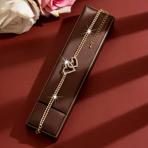 Primo piano elegante di una cavigliera a doppio cuore di strass su una scatola regalo