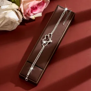 Dettaglio di un'elegante cavigliera d'argento a doppio filo con cuori di strass scintillanti.