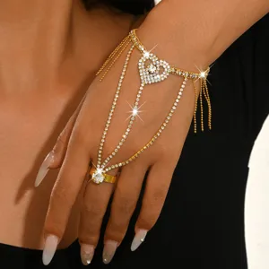 Close-up detail of a glamorous gold rhinestone heart slave bracelet with tassel design.