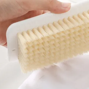 Cepillo de ropa de cerdas suaves para limpieza delicada de prendas, mango blanco.