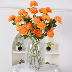 Bouquet de fleurs de renoncules artificielles orange en vase en verre pour decoration.