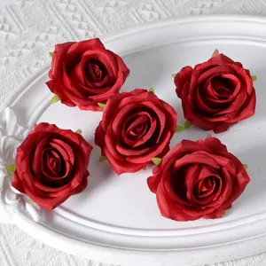Kunstmatige rode rozen bloemhoofdjes voor huwelijksdecoratie, zijden bloemstuk en feestboog achtergrond.