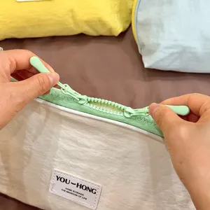 Close-up detail of white portable storage bag featuring smooth green zipper and brand label.