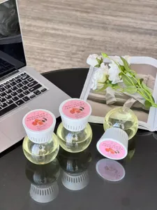 Close-up detail of inverted peach aromatherapy bottle diffuser on dark desk with floral decor.