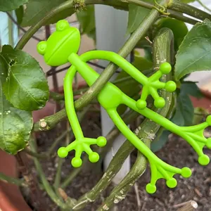 Froschförmiger flexibler Pflanzenhalter, der sich um einen grünen Stängel wickelt