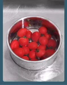 Détail du panier d'égouttoir de cuisine en acier inoxydable montrant le lavage des tomates.